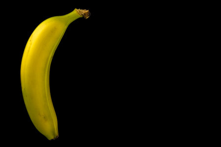 Ripe single banana arranged on black background, modern art banana fruit on black tableの写真素材