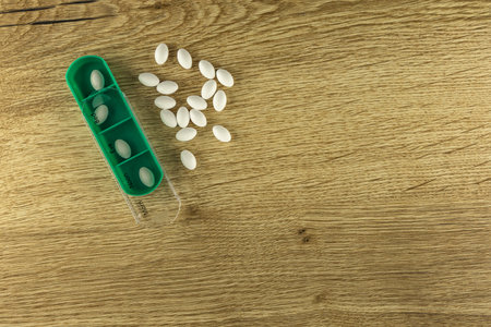 Prescription medications, white pills scattered on the table, arranging medications in the medication container by day of the weekの写真素材