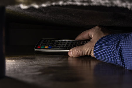 TV remote control under the couch, man takes out a remote control from under the couch, searching...