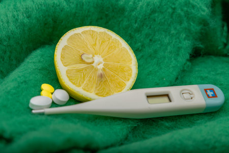 Electronic thermometer, painkillers, paracetamol medicine for fever, vitamins, yellow lemon cut in half, realistic photoの写真素材