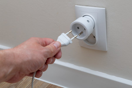 A man plugs a plug into a socket, a man's hand inserting a plug into the holes of a smart socket, an...