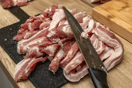 Bacon cut into thin pieces, bacon cubes, preparing ingredients for lard in the kitchen, wooden...