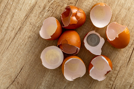 Chicken eggshells placed on a wooden counter in the kitchen, coins placed inside the eggs