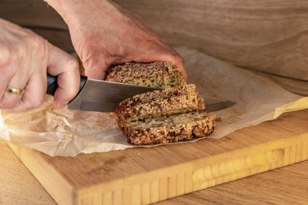 Homemade pumpkin bread with sunflower seeds, flax seeds, sesame seeds, placed on a chopping board in...