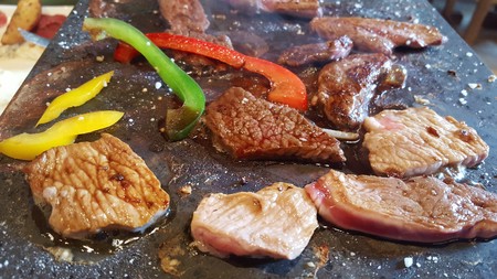 A French hot stone  "stone grill" with slices of meat and vegetables to cook without using fat.の写真素材