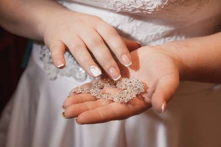 Elegant bride holding silver earrings. Tender hands with ringsの写真素材