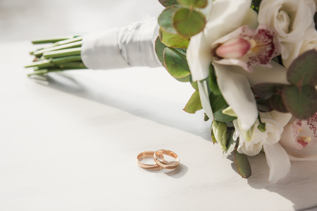 Wedding rings with beautiful wedding bouquet on a white backgroundの写真素材