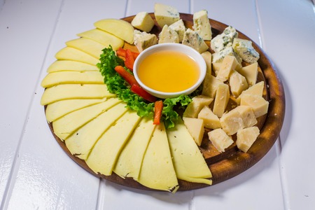 Different cheese on the table with honey and vegetablesの写真素材
