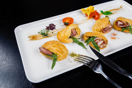 Mousse of cheese with bacon in eclair, served on a plate and covered with green and tomato cherryの写真素材