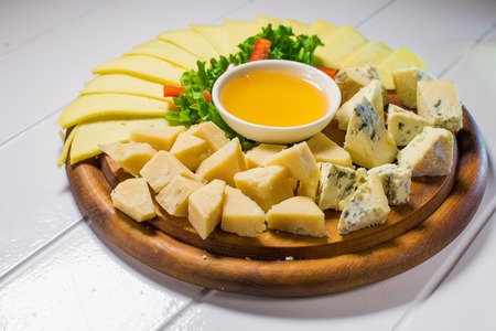 Different cheese on the table with honey and vegetablesの写真素材
