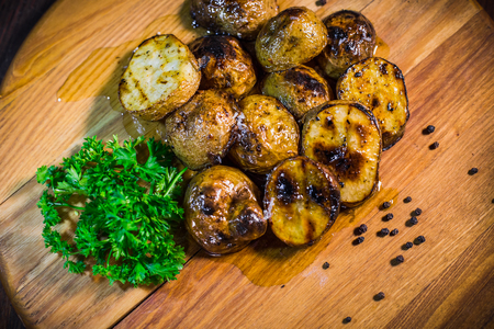 Baked potatoes with parsley and garlic on a wooden tableの写真素材