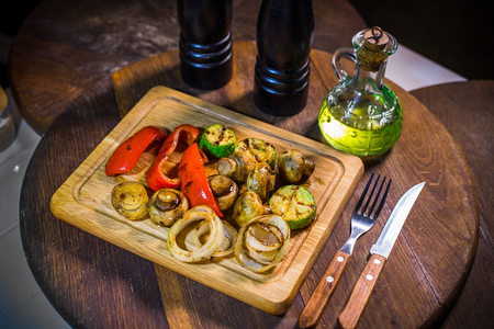 Grilled vegetables, zucchini, red pepper, champignons, onions on a wood boardの写真素材