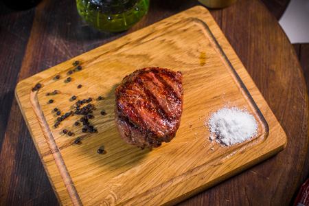 Grilled pork rib chop steak in a clay plate with oil, mustard, salt and rosemary is an old wooden background.の写真素材