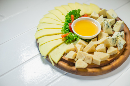 Different cheese on the table with honey and vegetablesの写真素材