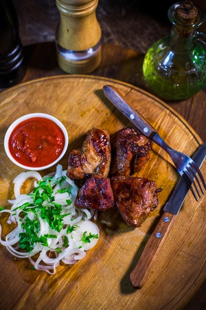 Barbecue skewers with juicy meat and sauce on plate, closeup on a wood backgroundの写真素材