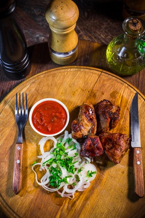 Barbecue skewers with juicy meat and sauce on plate, closeup on a wood backgroundの写真素材