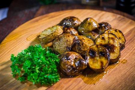 Baked potatoes with parsley and garlic on a wooden tableの写真素材