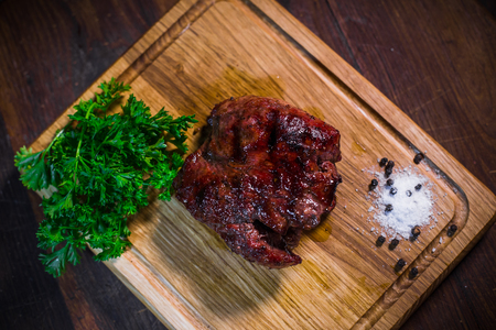 Grilled pork rib chop steak in a clay plate with oil, mustard, salt and rosemary is an old wooden background.の写真素材