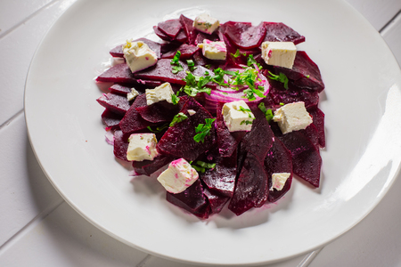 Vitamin salad with beets and Feta cheese in a white plate on a wooden backgroundの写真素材