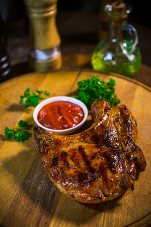 Sliced grilled beef barbecue steak on cutting board on dark wooden backgroundの写真素材