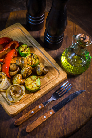 Grilled vegetables, zucchini, red pepper, champignons, onions on a wood boardの写真素材