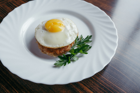 Fried eggs on a plate, decorated with greenery with a wooden backgroundの写真素材