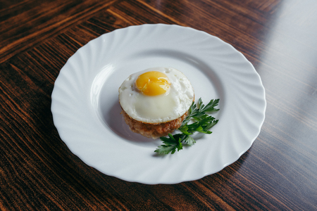 Fried eggs on a plate, decorated with greenery with a wooden backgroundの写真素材