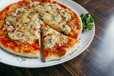 Hot pizza slice with melting cheese on a rustic wooden table.の写真素材