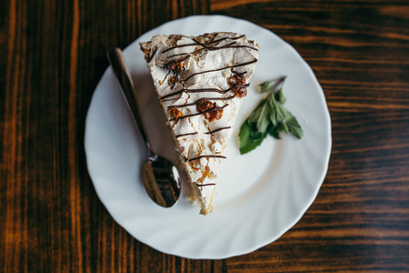 Slice of cake with chopped nuts on wooden chopping board