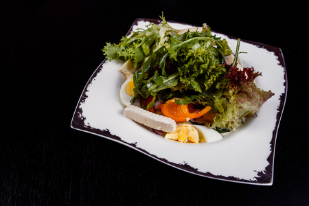 A colorful, tasty and healthy vegetable salat with red tomatoes, green cucumbers and pepper slices, white and yellow cheese, eggs and pesto sauceの写真素材