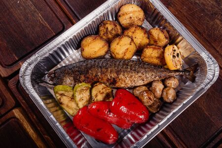 Appetizing mackerel fish baked on fire with spices, served on a plate and decorated with vegetablesの写真素材