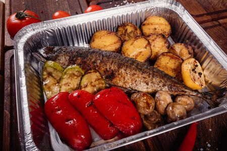 Appetizing mackerel fish baked on fire with spices, served on a plate and decorated with vegetablesの写真素材