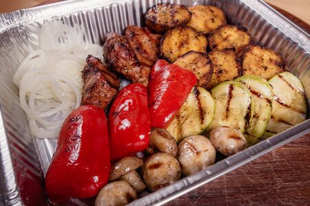 Grilled potatoes with grilled vegetables and meat on a baking tray as a studio shot