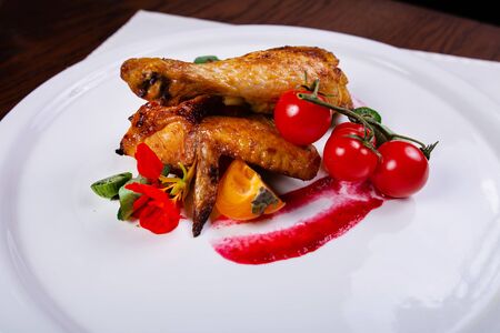 Baked chicken and shin wing, decorated with a slice of persimmon, kiwi, tomatoesの写真素材