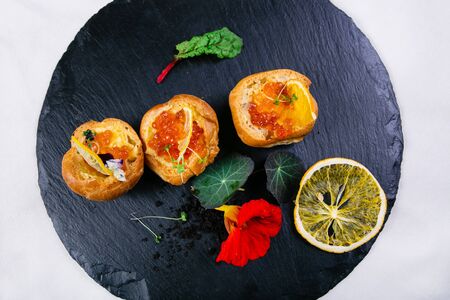 Sandwiches with butter and red caviar, decorated with greens, with lemon slices, a mint leaf, a...