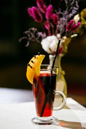 Festive mulled wine in a glass decorated with a slice of an orange on a white backgroundの写真素材
