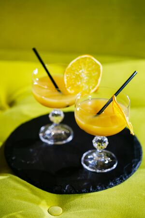 Attractive women are talking in cafeteria and drinking juice. They are smiling. Focus on glasses of orange juice with tubules.の写真素材