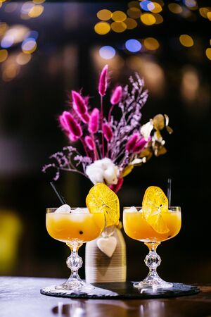 Attractive women are talking in cafeteria and drinking juice. They are smiling. Focus on glasses of orange juice with tubules.の写真素材