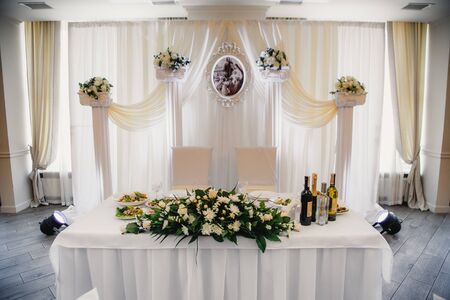 festive table for the bride and groom decorated with cloth and flowers in wedding dayの写真素材