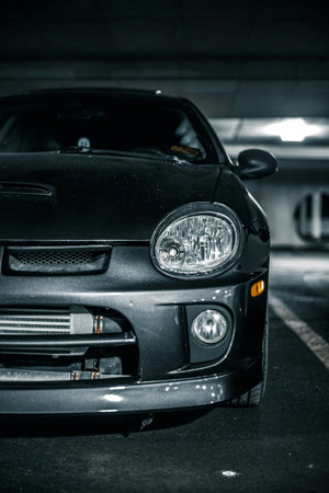 The headlight of a black car in the parking lot. Toned.の写真素材