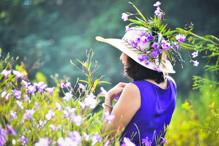 Young woman in a hat with a bouquet of purple flowers.の写真素材