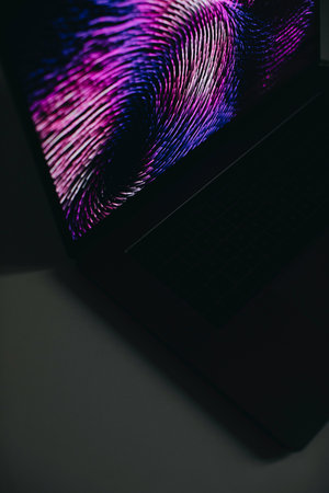 Laptop with glowing screen on black background, close-up.の写真素材