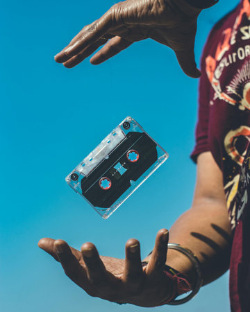 Cassette tape in the hands of a man against the blue skyの写真素材