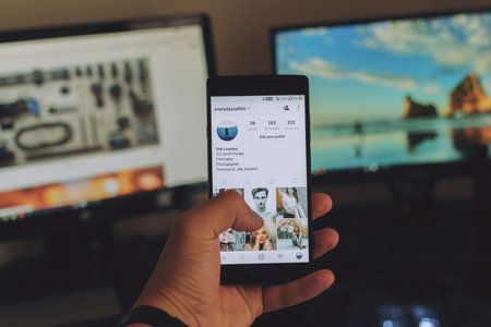 Man hand holding smartphone with application on the screen. It is a photo-sharing social networking...