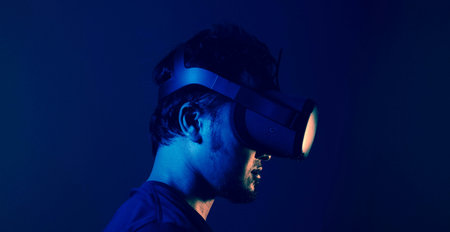 Young man using virtual reality headset. Studio shot on dark blue background.の写真素材