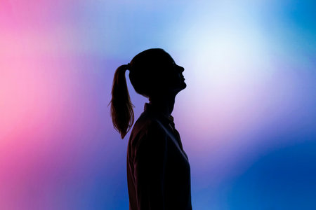 Silhouette of a girl with pigtails in the studio on a colored background