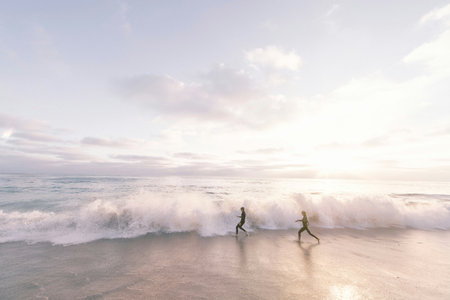 Couple running on the beach at sunsetの写真素材