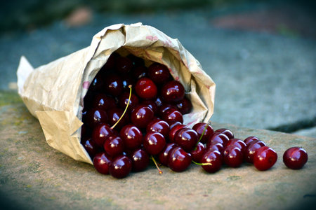 Cherries in a paper bag on the ground. Toned.