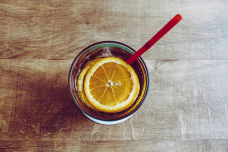 A glass of cola with a straw and a slice of orange