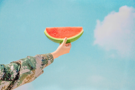 Watermelon in the hands of a person on a blue sky backgroundの写真素材